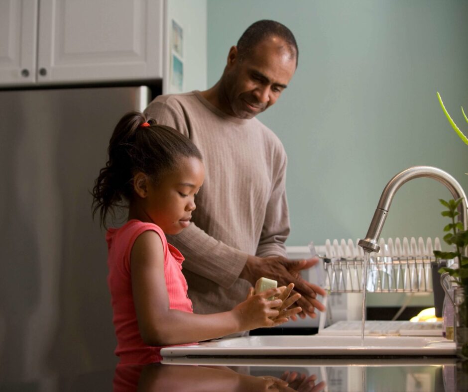 Family washing hands at kitchen sink