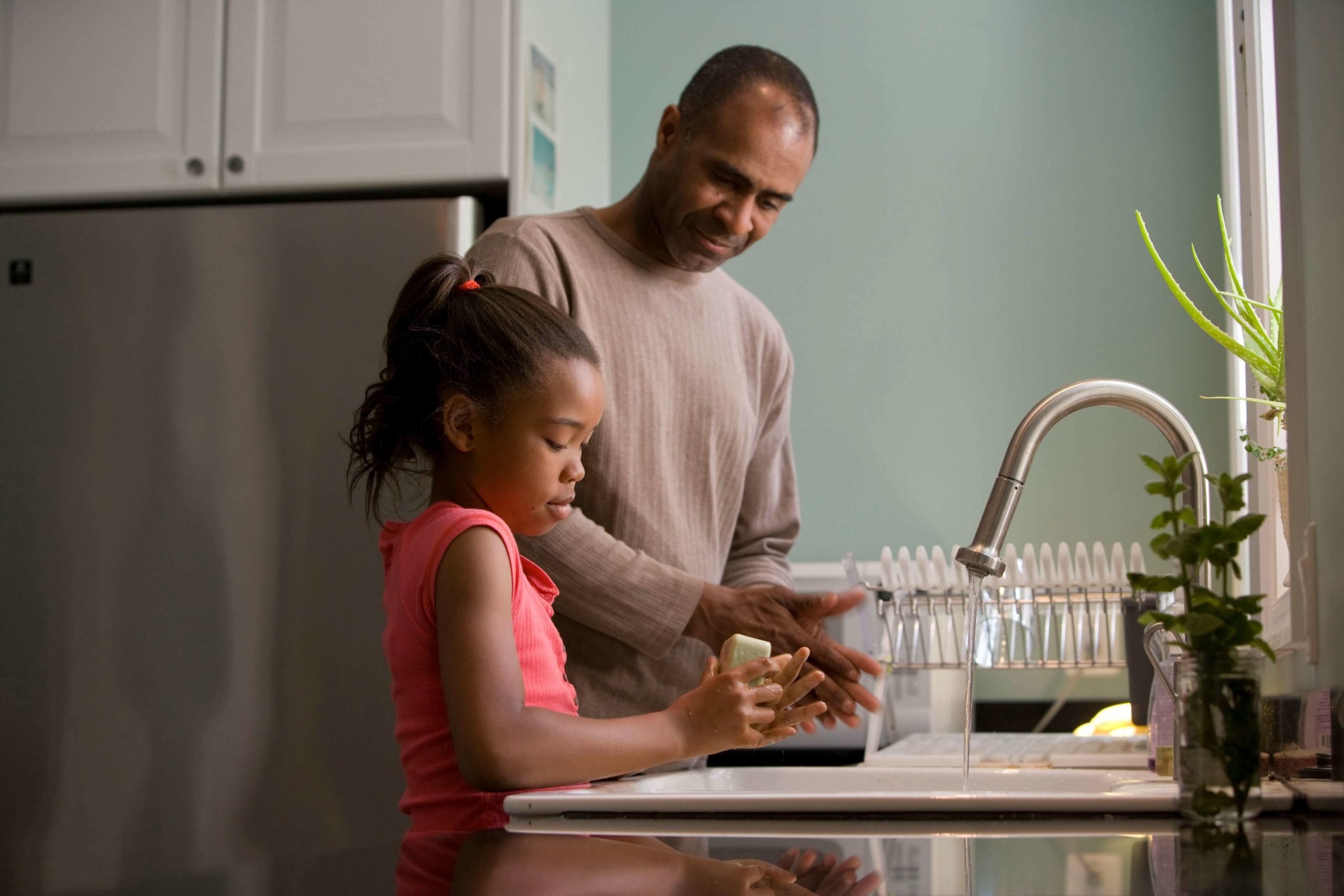 Family washing hands at kitchen sink